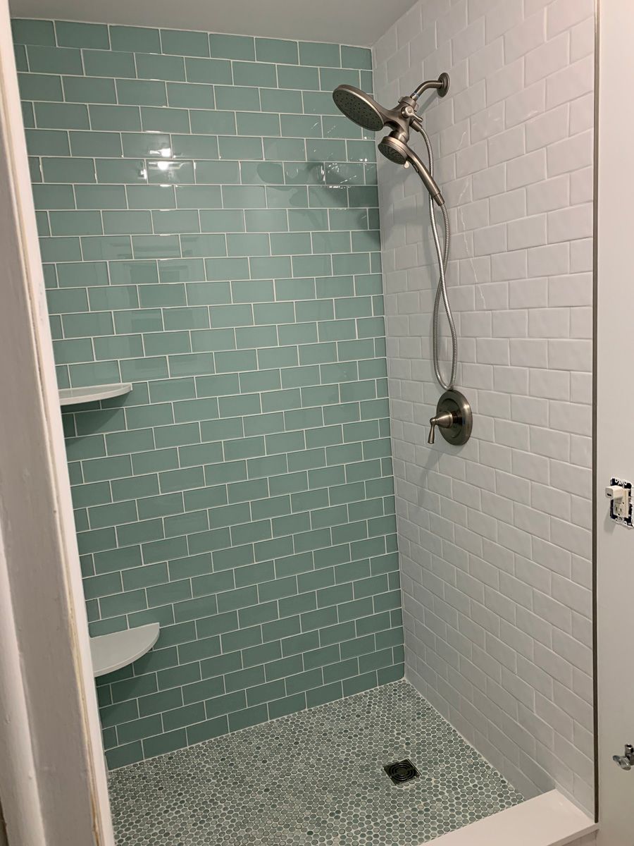 A shower with blue tiles and a shower head.