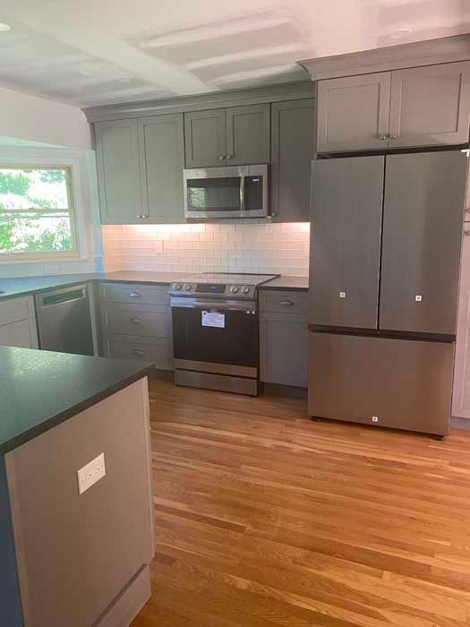 A kitchen with stainless steel appliances and gray cabinets.