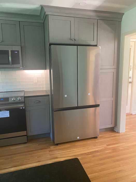 A kitchen with stainless steel appliances and gray cabinets.