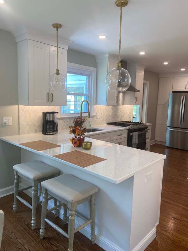 A kitchen with white cabinets , white counter tops , stainless steel appliances and a large island.
