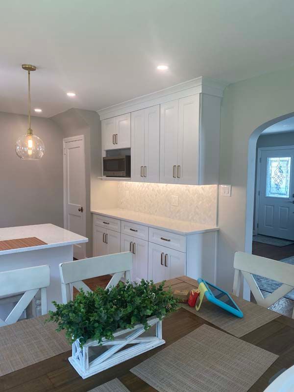 A kitchen with white cabinets and a table with a plant on it.