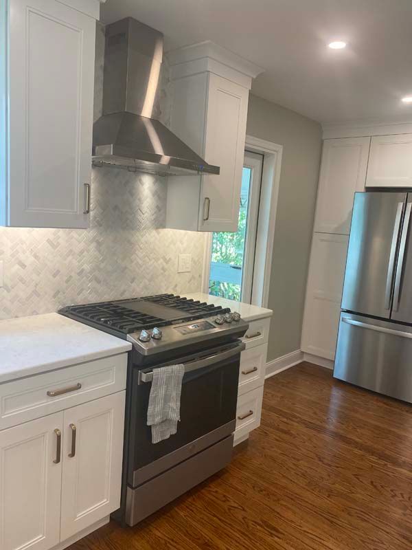 A kitchen with stainless steel appliances and white cabinets.