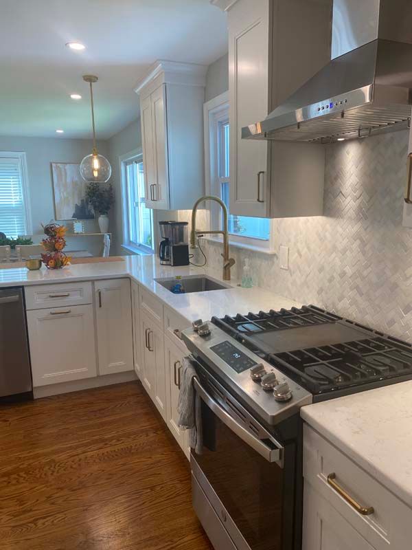 A kitchen with white cabinets , a stove , a sink , and a dishwasher.