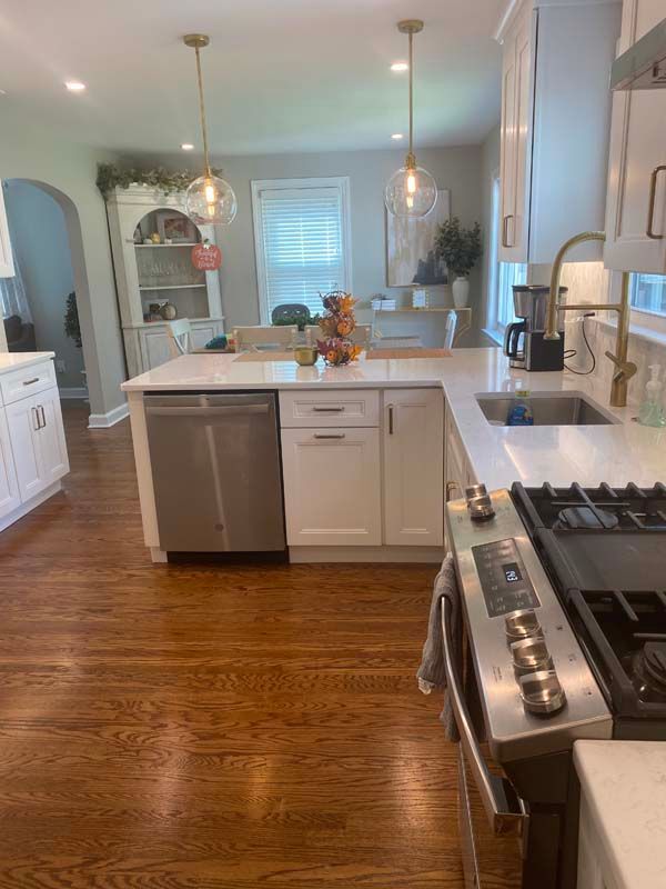A kitchen with white cabinets , a stove , a sink , and a dishwasher.