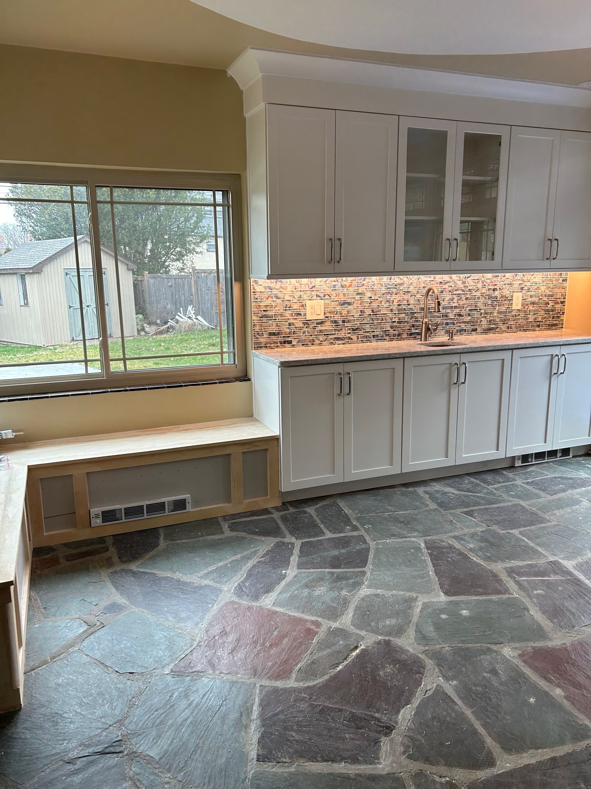 A kitchen with white cabinets and a stone floor
