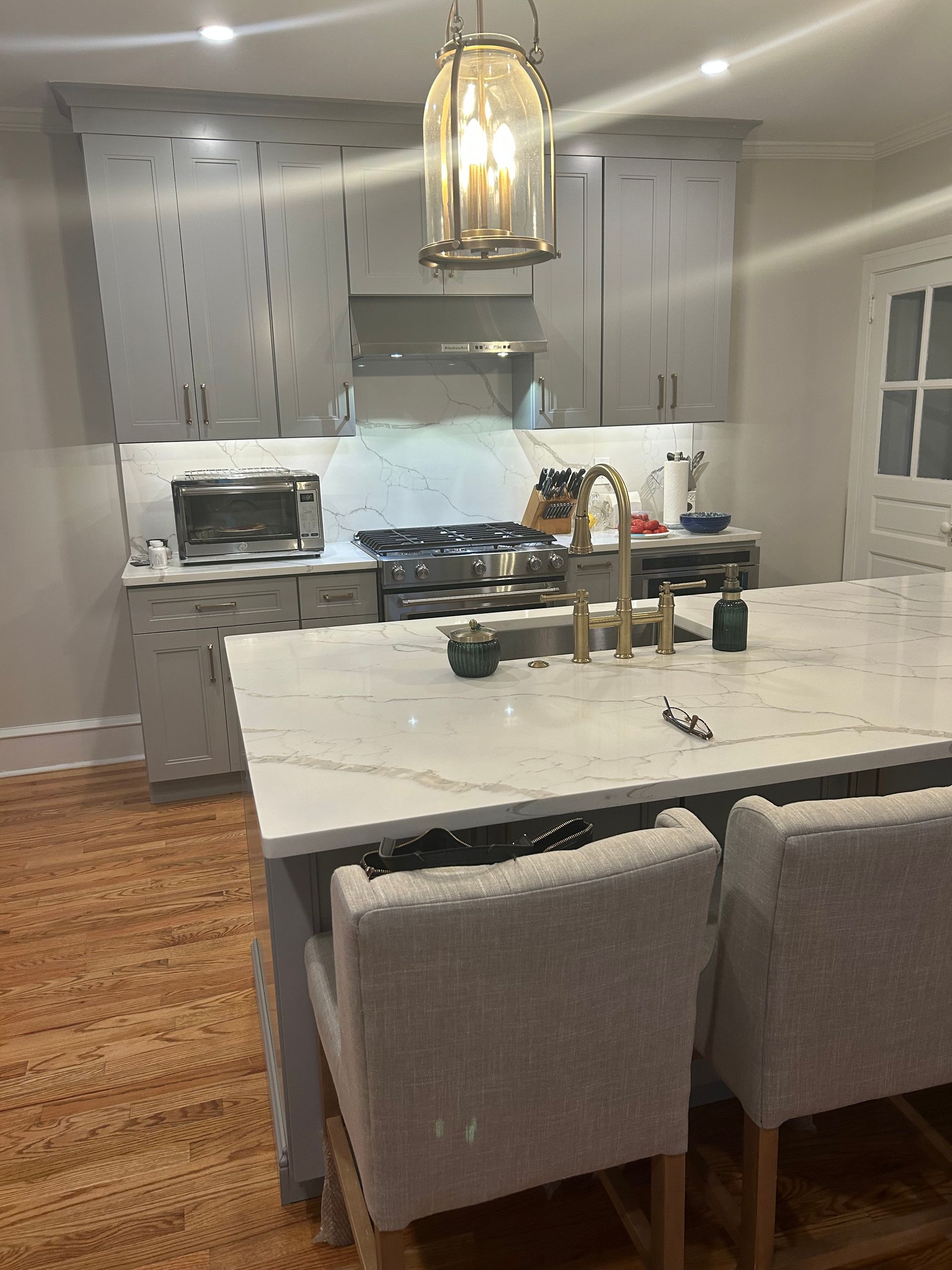 A kitchen with a large island and chairs and a stove.