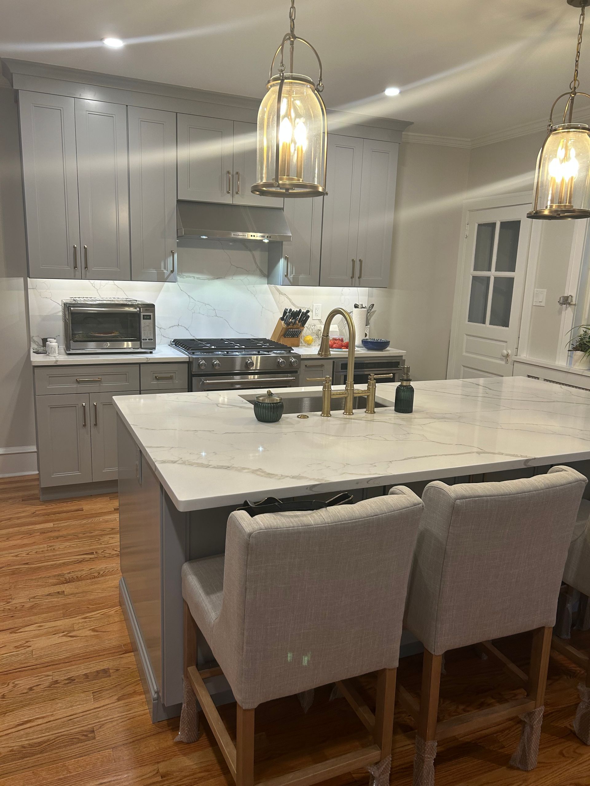 A kitchen with a large island and chairs and a stove.