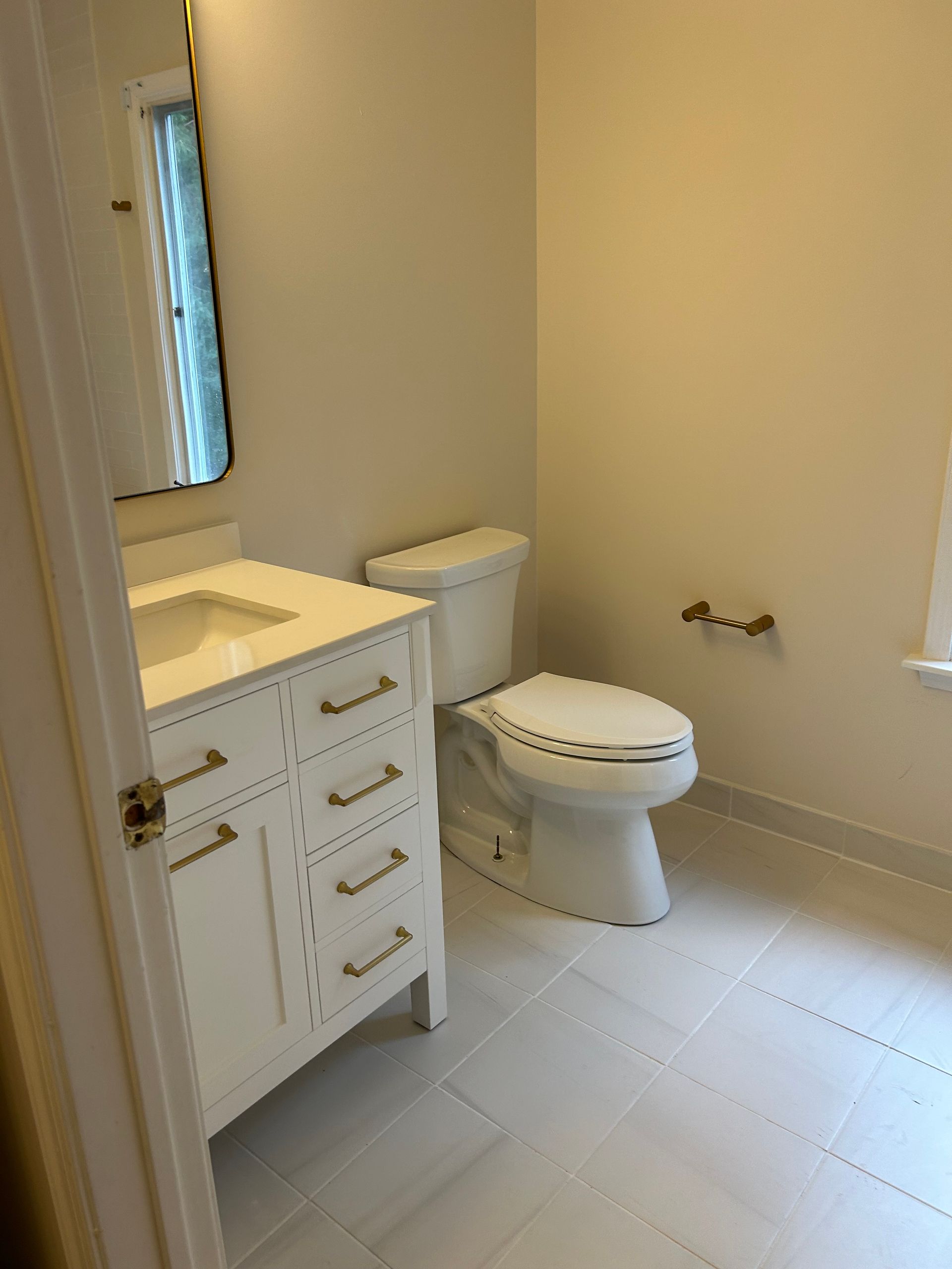 A bathroom with a toilet , sink and mirror.