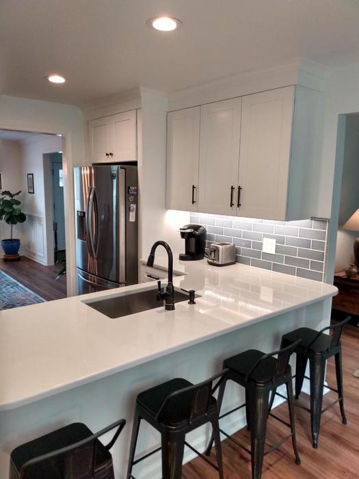 A kitchen with a sink , stools and a refrigerator