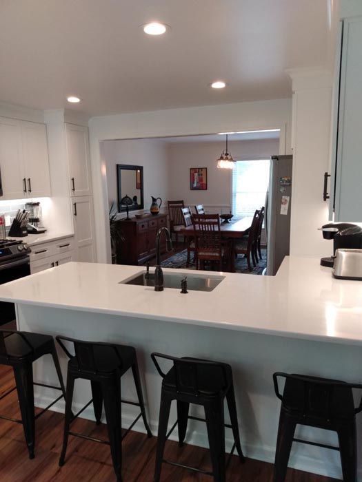 A kitchen with white cabinets and black stools