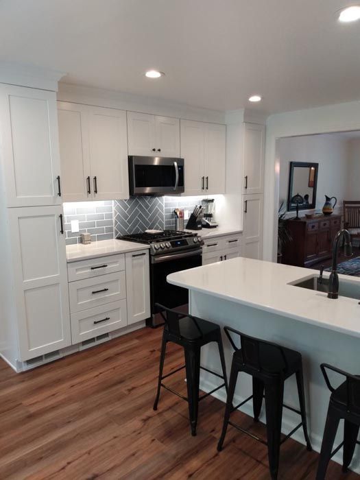 A kitchen with white cabinets and hardwood floors