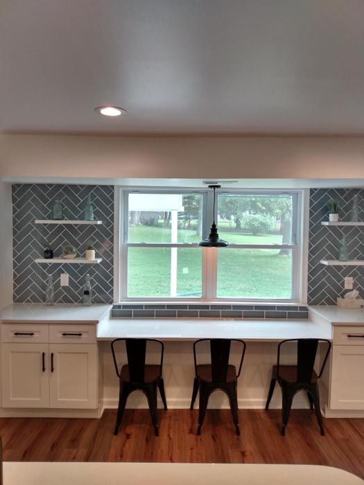 A kitchen with two tables and chairs under a window