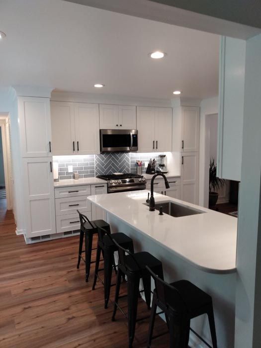 A kitchen with white cabinets and black stools