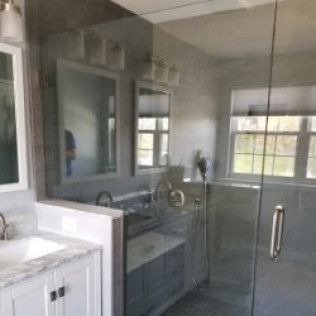 A bathroom with a sink , mirror and shower with a glass door.
