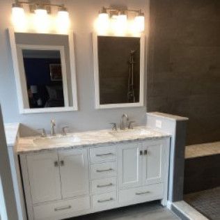 A bathroom with two sinks , two mirrors , and a shower.