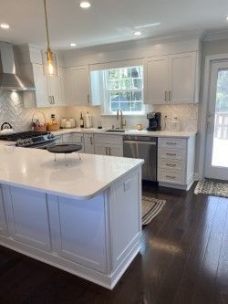 A kitchen with white cabinets , stainless steel appliances , and a large island.