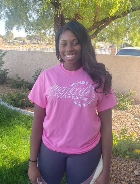 Woman in pink shirt and leggings smiles outdoors.