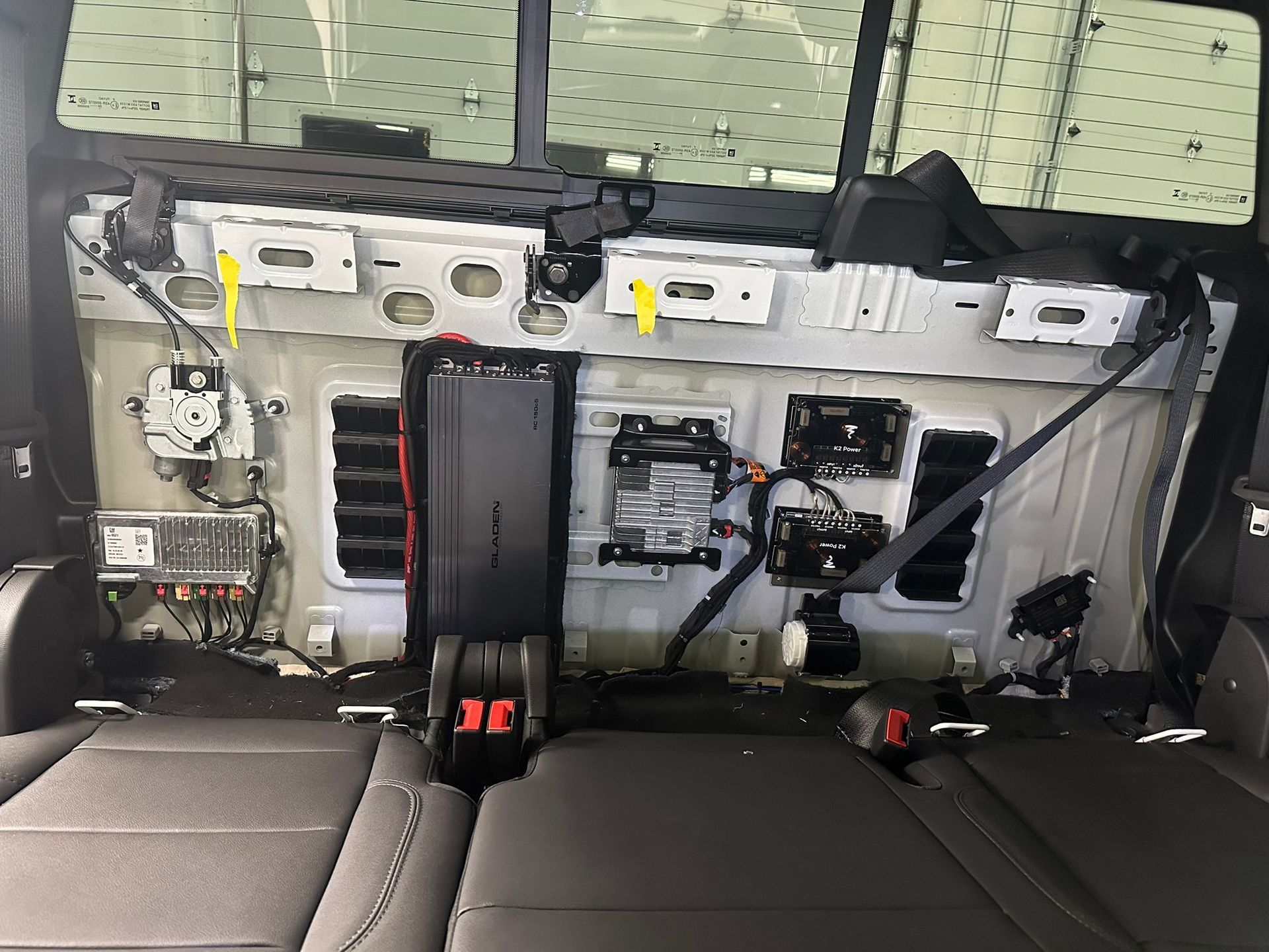 Interior of a truck's rear wall with various components exposed, including vents, electronic devices, and seatbelts.