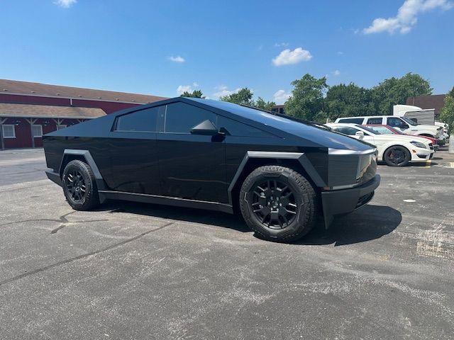 Black Tesla Cybertruck parked on asphalt on a sunny day.