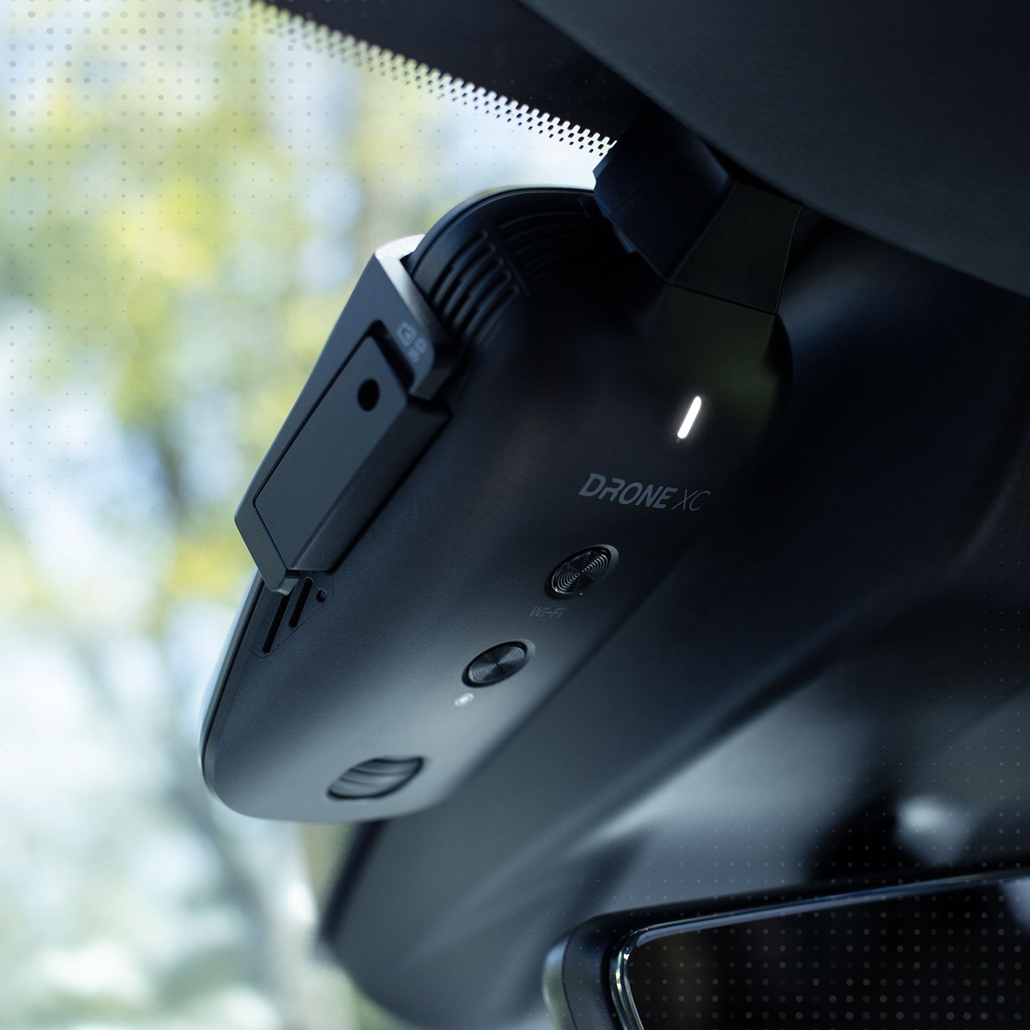 Black car dash camera attached to windshield, with a green light indicator.