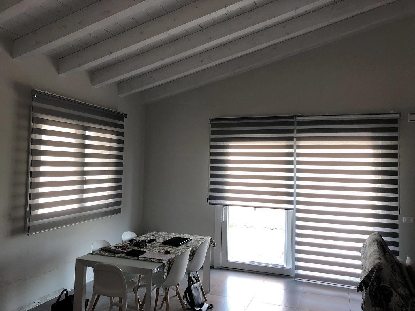 Un soggiorno con tavolo, sedie e tende alle finestre.