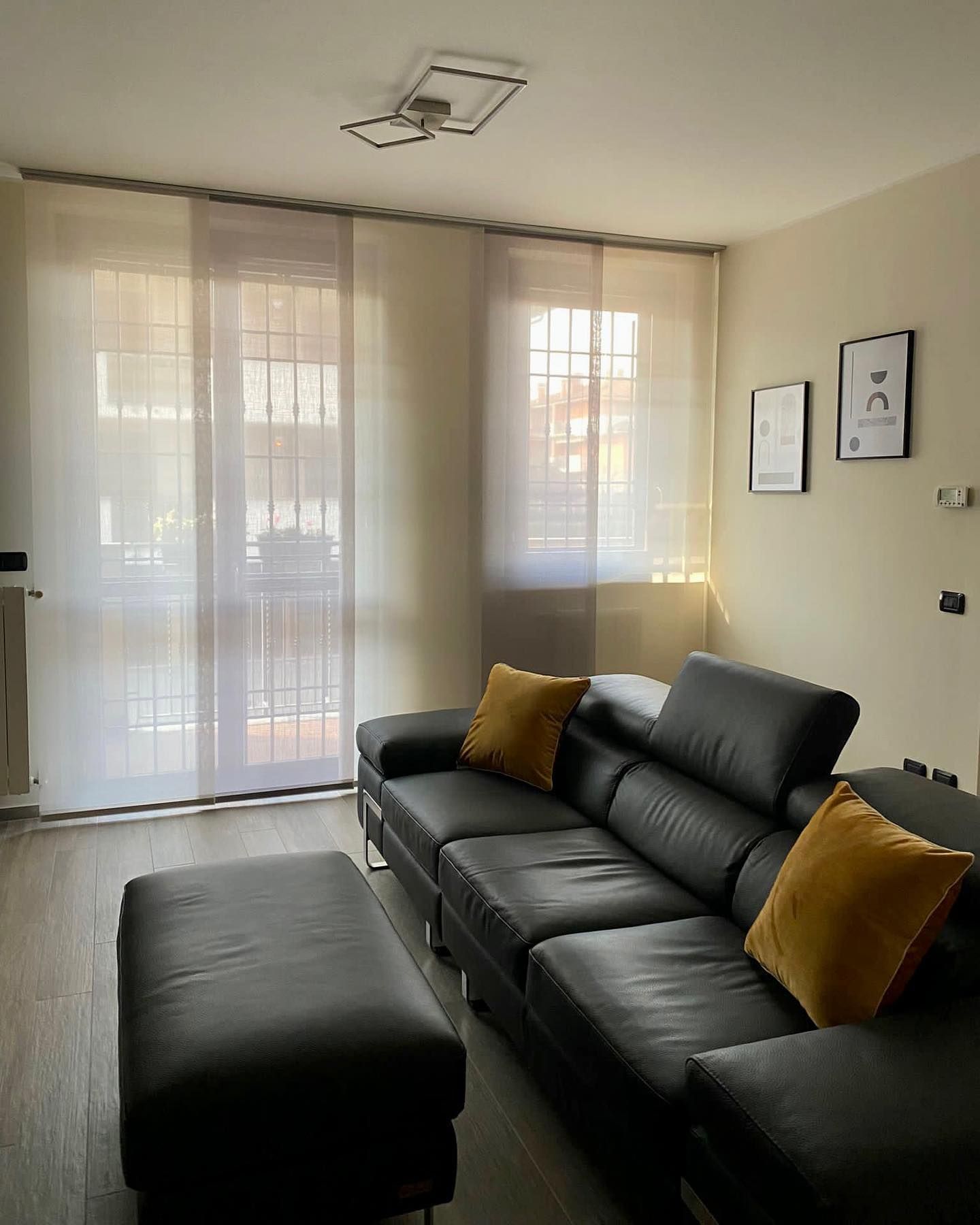 Un soggiorno con un divano in pelle nera e cuscini gialli