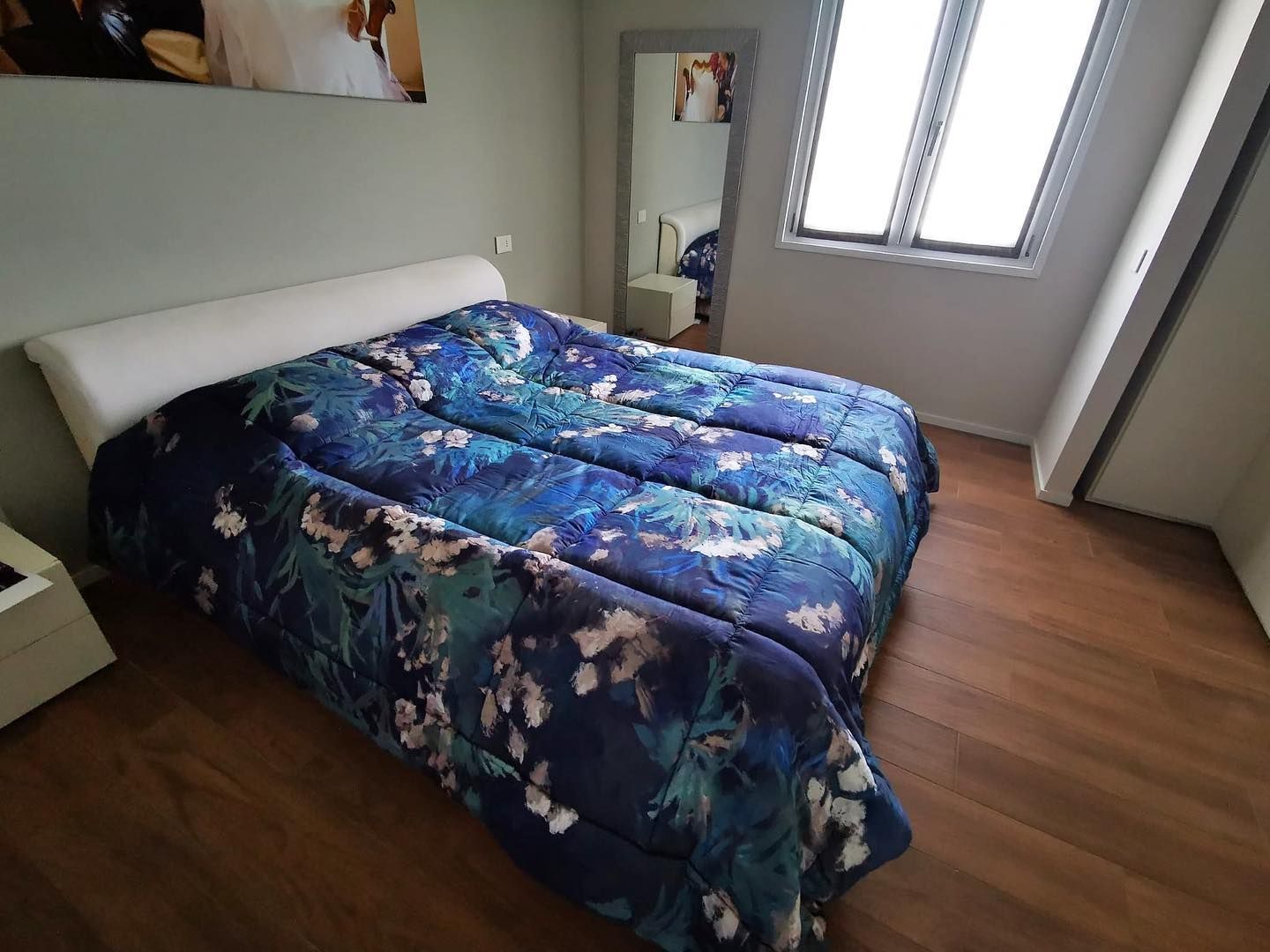 Una camera da letto con un piumone blu e uno specchio