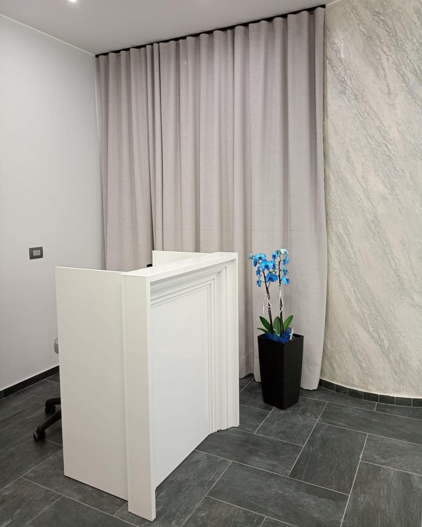 Una reception bianca in una stanza con un vaso di fiori.