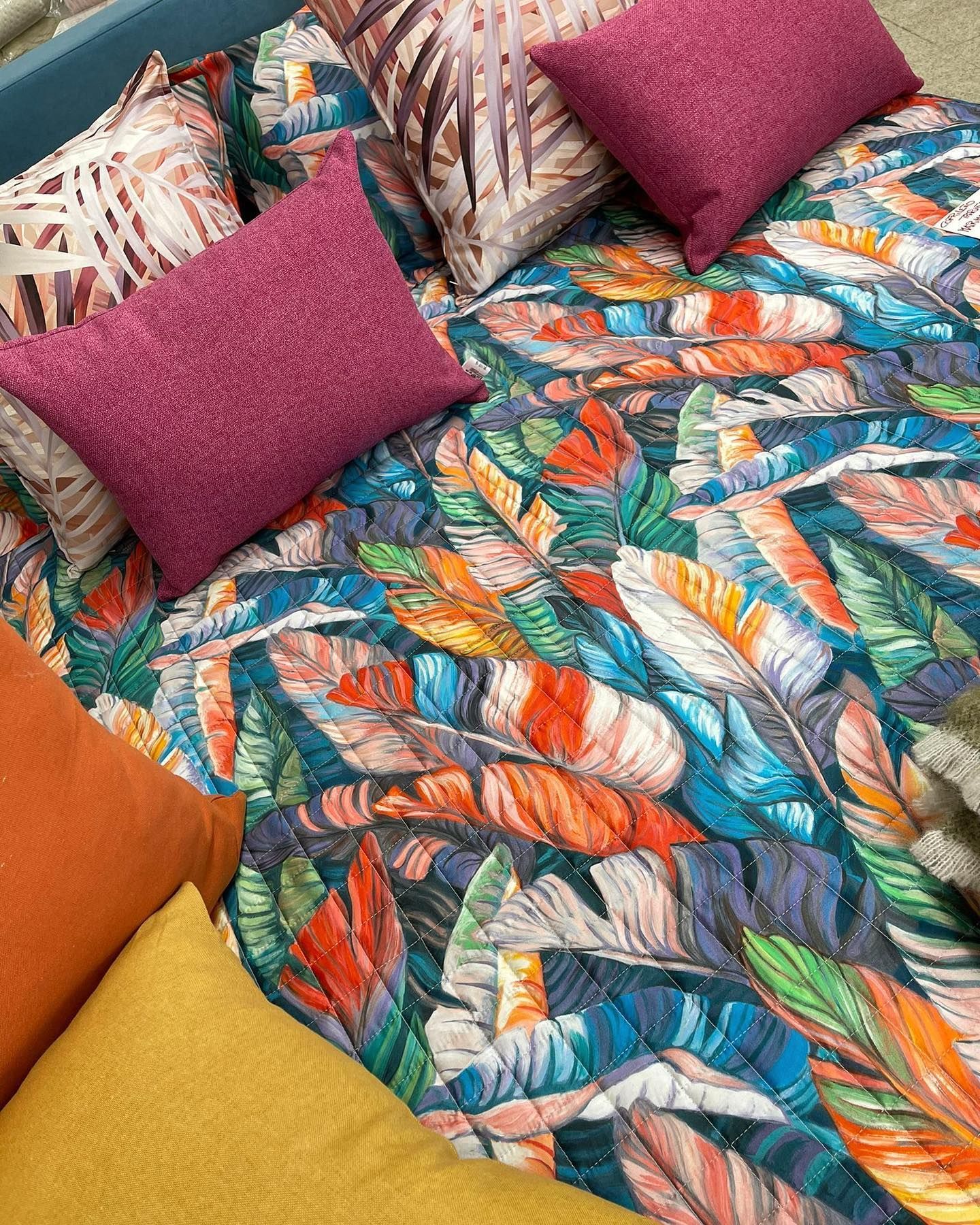 Un letto con un piumone colorato e dei cuscini.