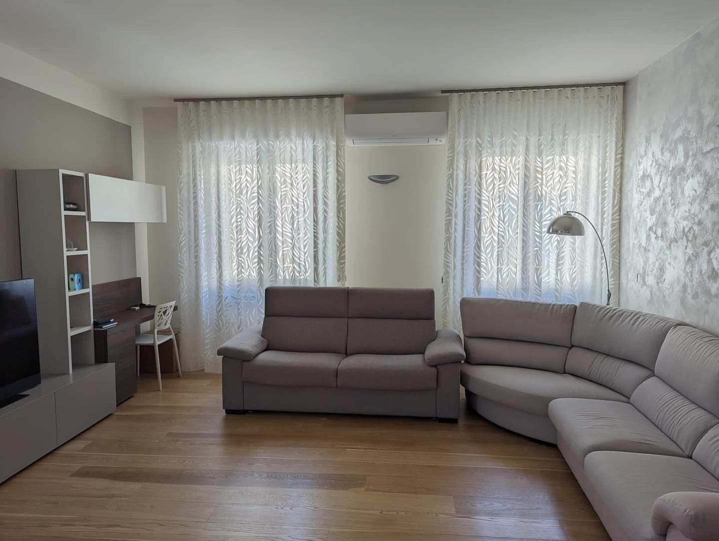 Un soggiorno con un grande divano componibile e una TV a schermo piatto.