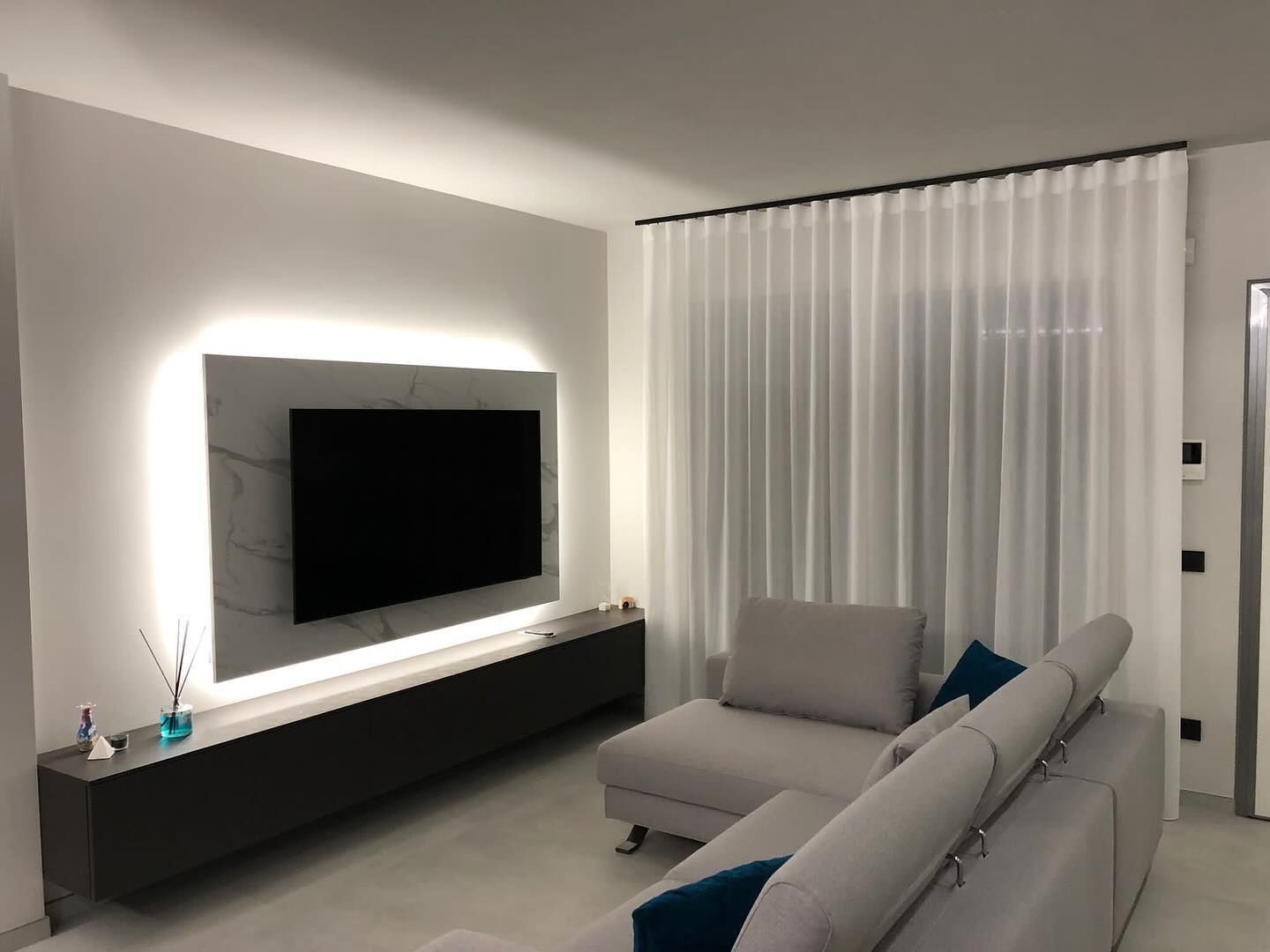 Un soggiorno con un divano e una TV a schermo piatto sulla parete.