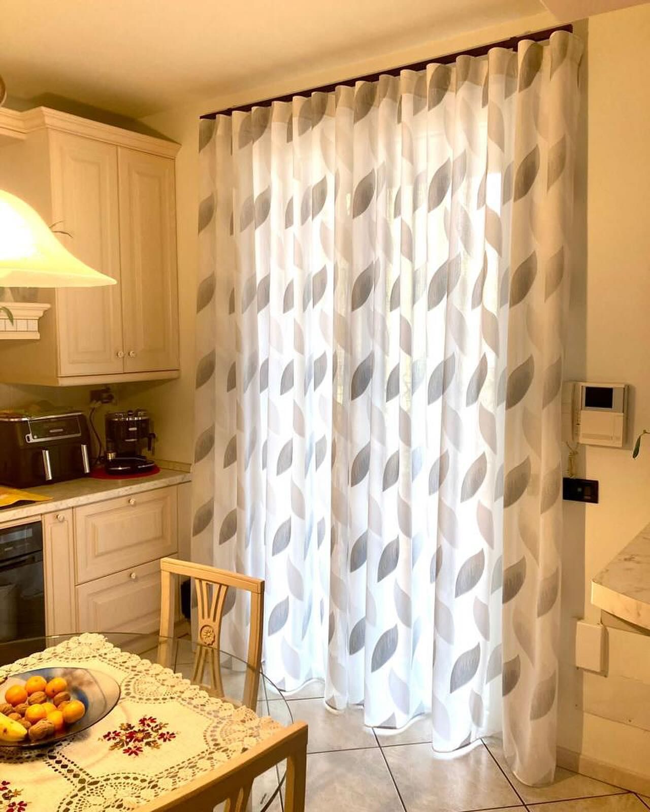 Una cucina con tavolo, sedie e tende alla finestra.