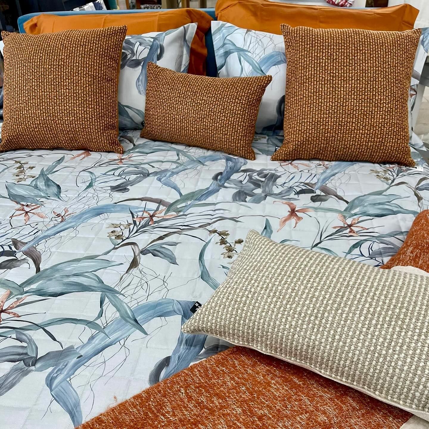 Un letto con un piumone floreale e cuscini sopra