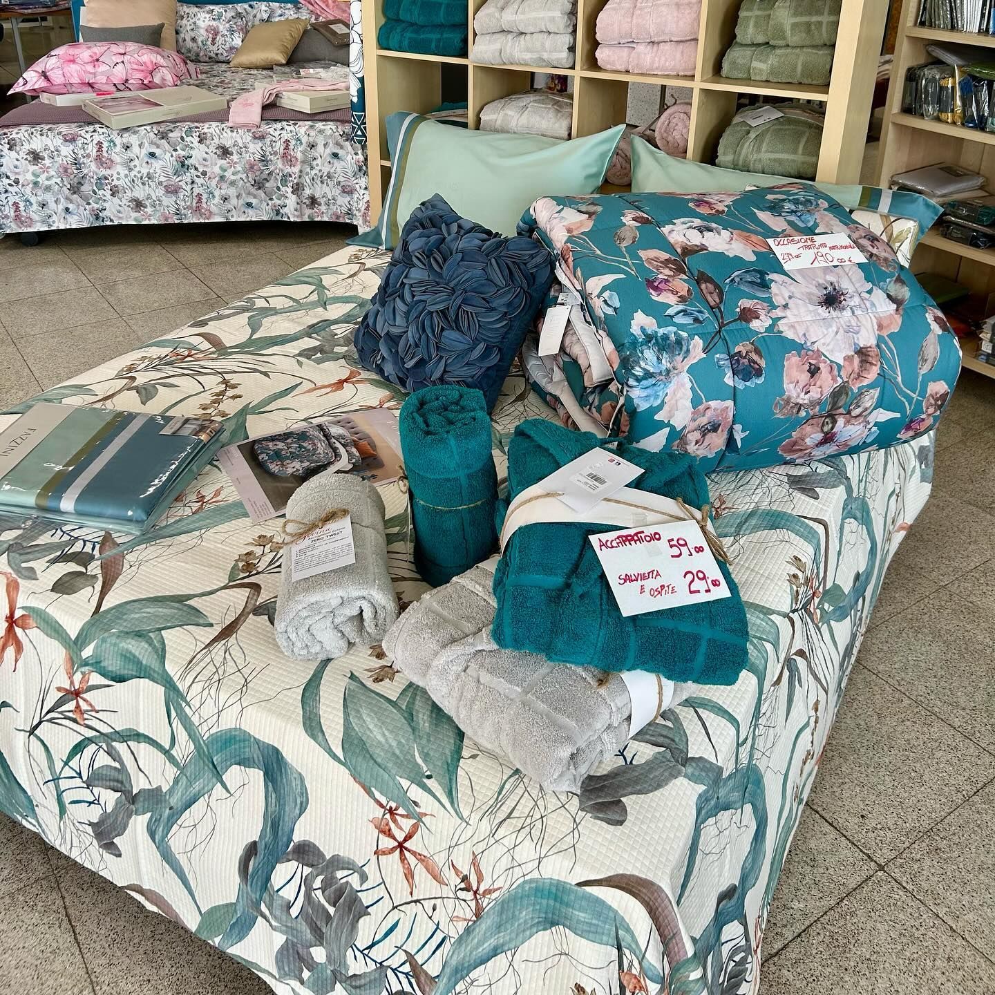 Un letto con un piumone floreale e cuscini in un negozio.