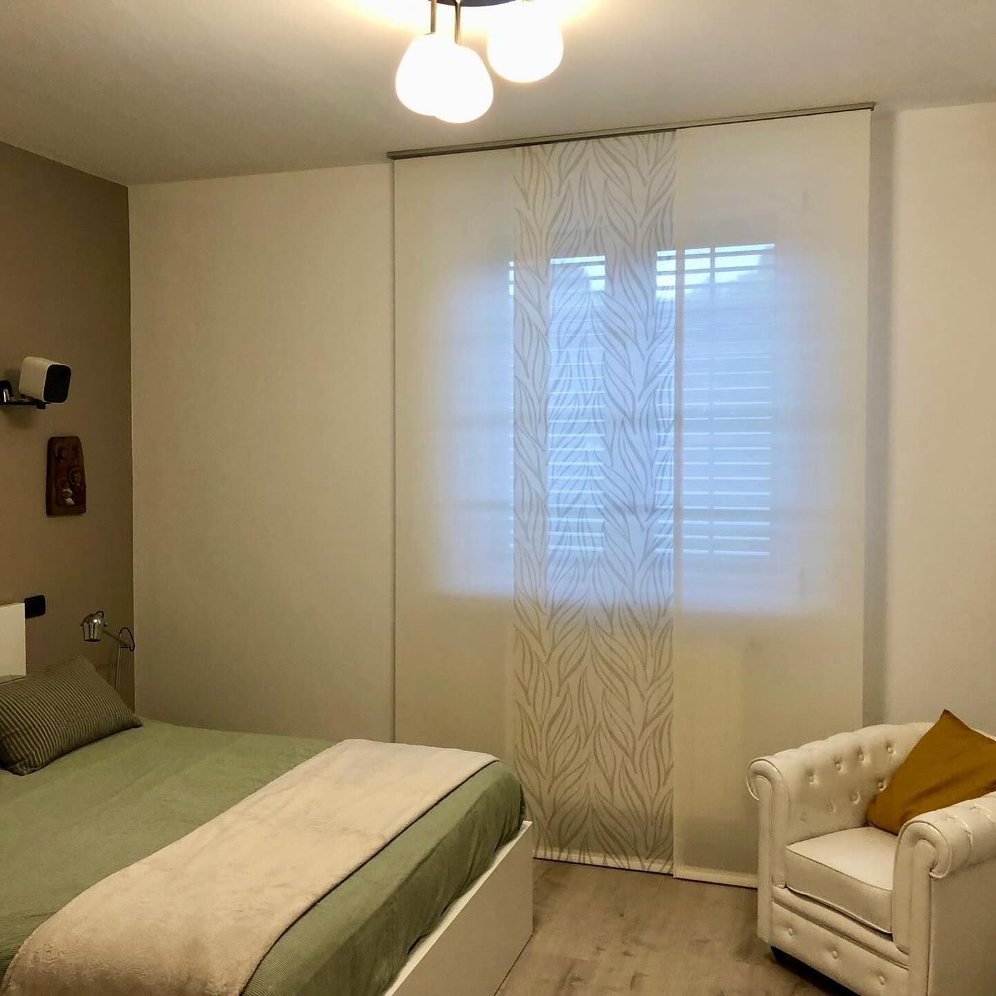 Una camera da letto con un letto, una sedia e una finestra.