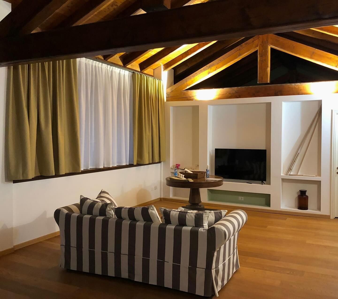 Un soggiorno con un divano a righe e una TV a schermo piatto