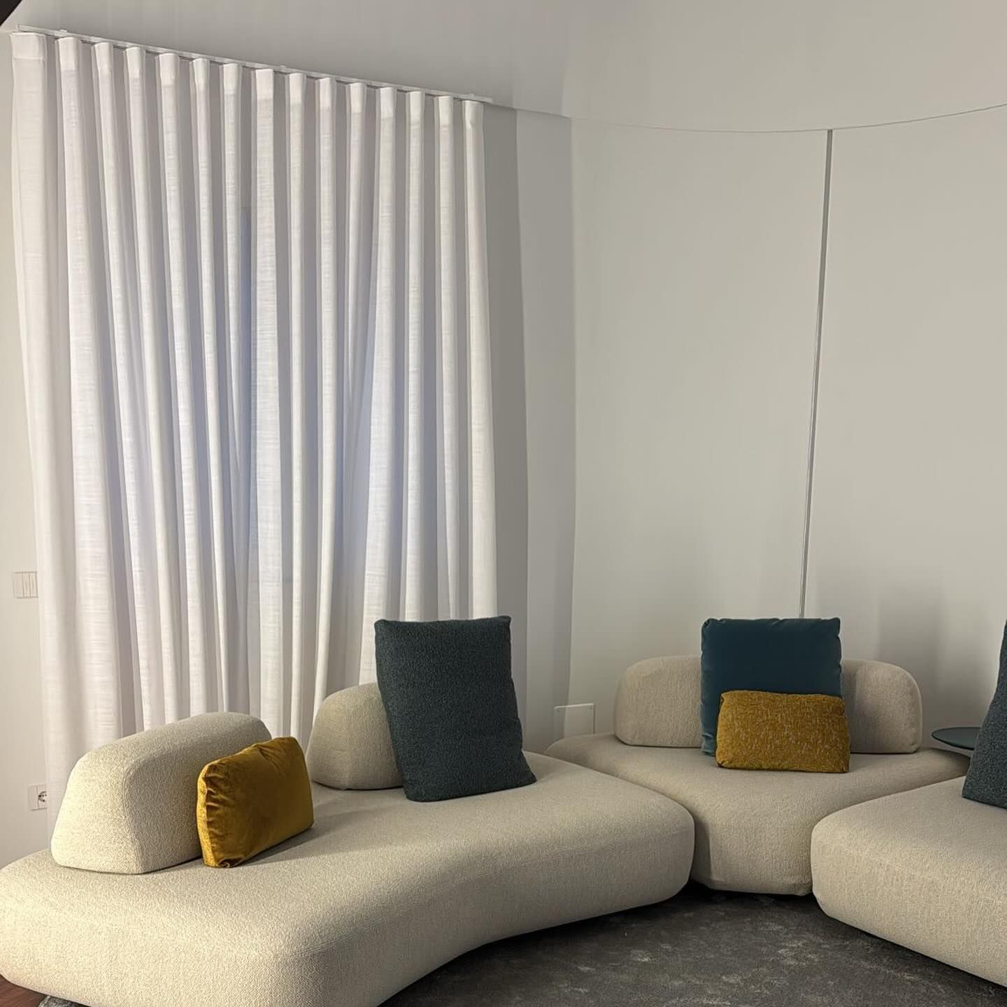 Un soggiorno con un divano e una finestra con tende bianche