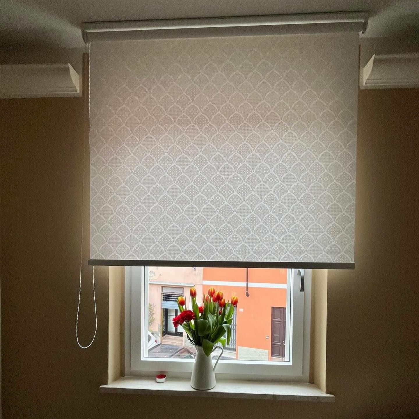 Una finestra con una tenda bianca e un vaso di fiori sul davanzale