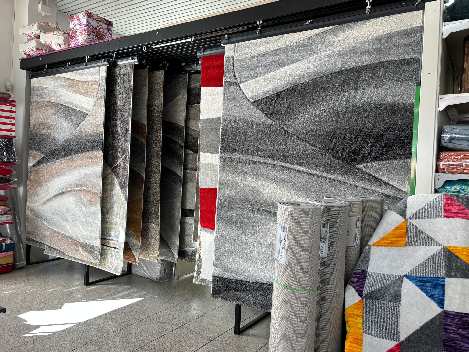 Un mucchio di tappeti sono appesi su uno scaffale in un negozio.