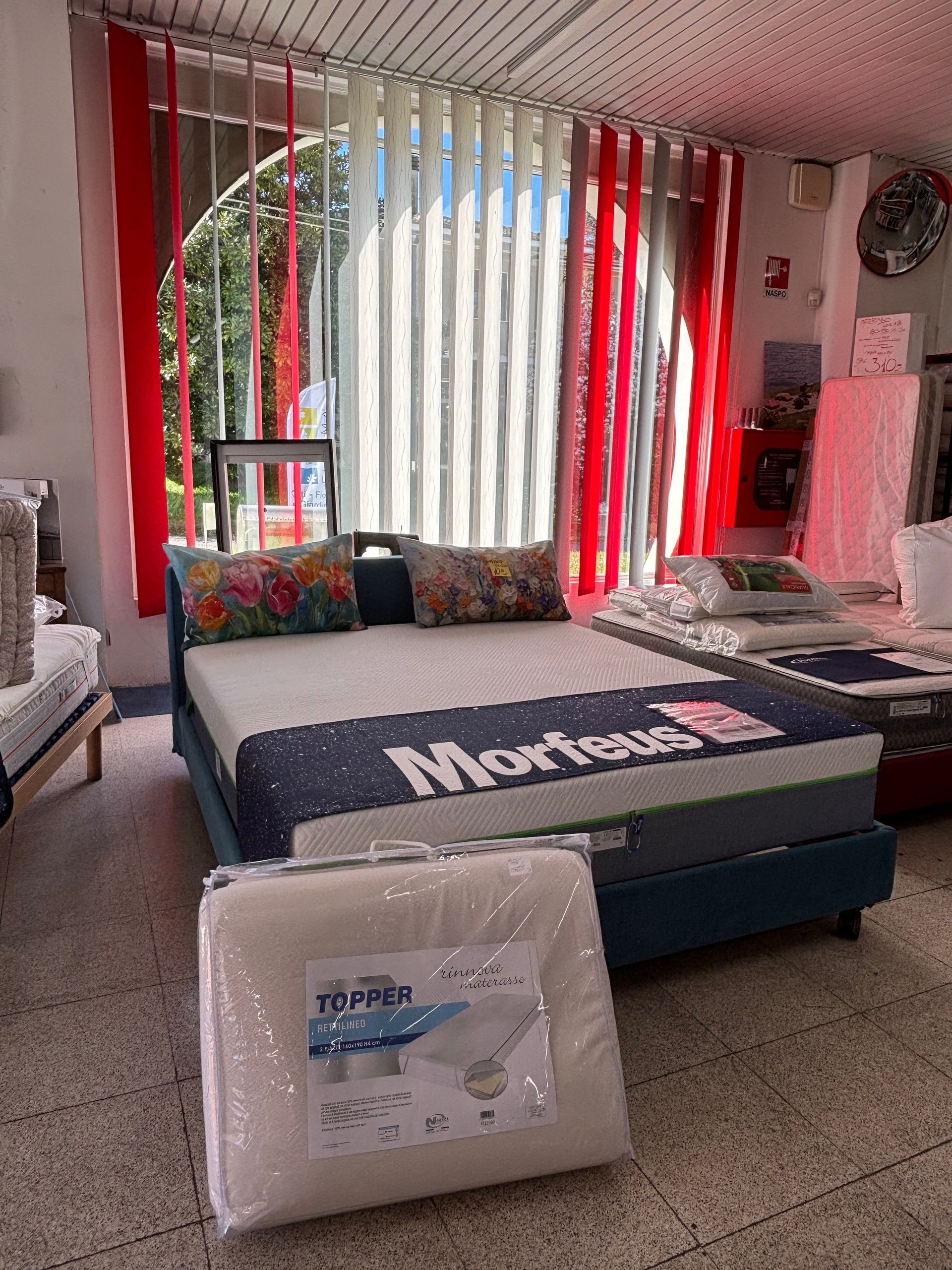 Un letto con un materasso sopra si trova in una stanza con molte finestre.