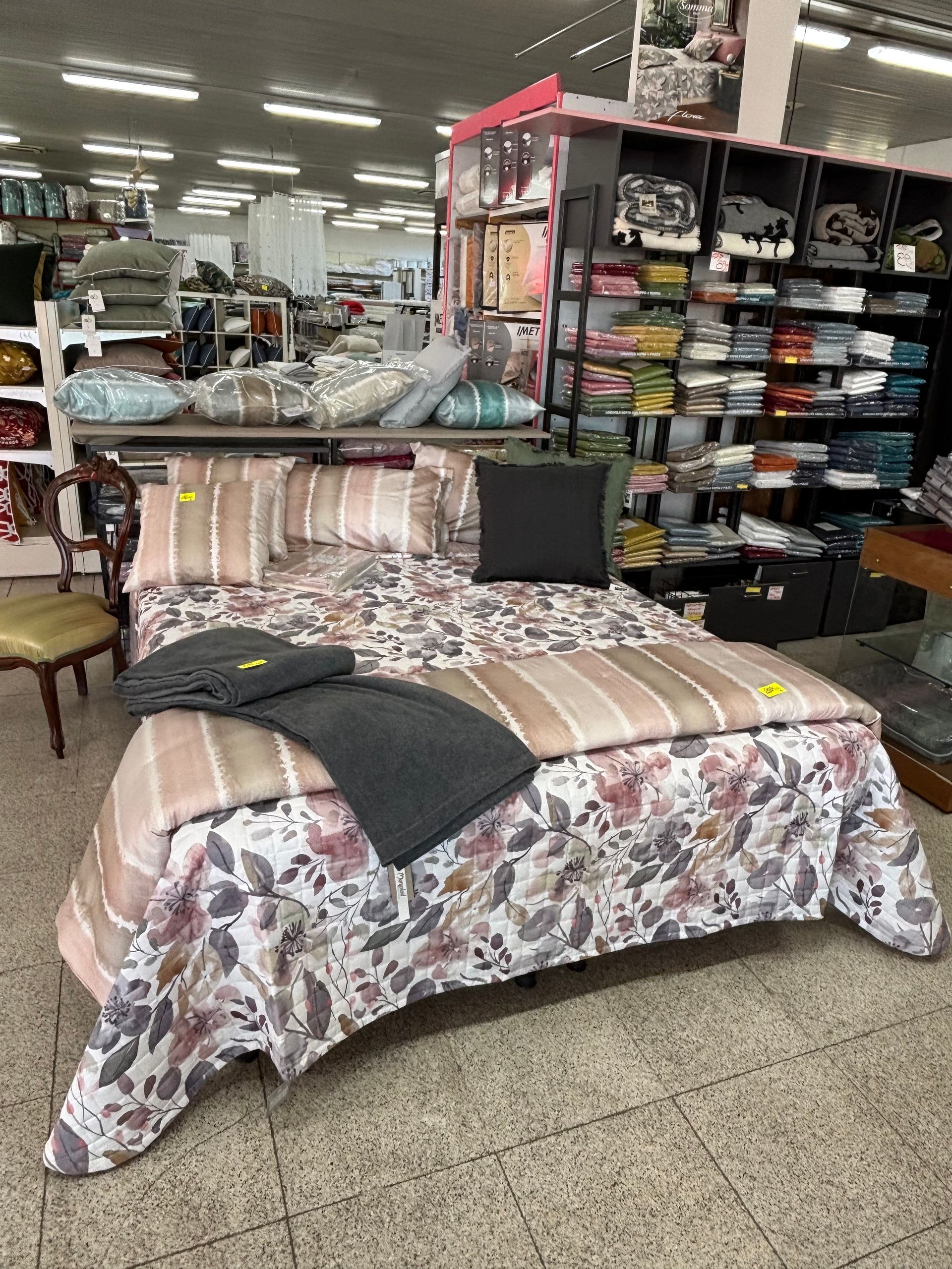 Un letto con piumone e cuscini in un negozio.