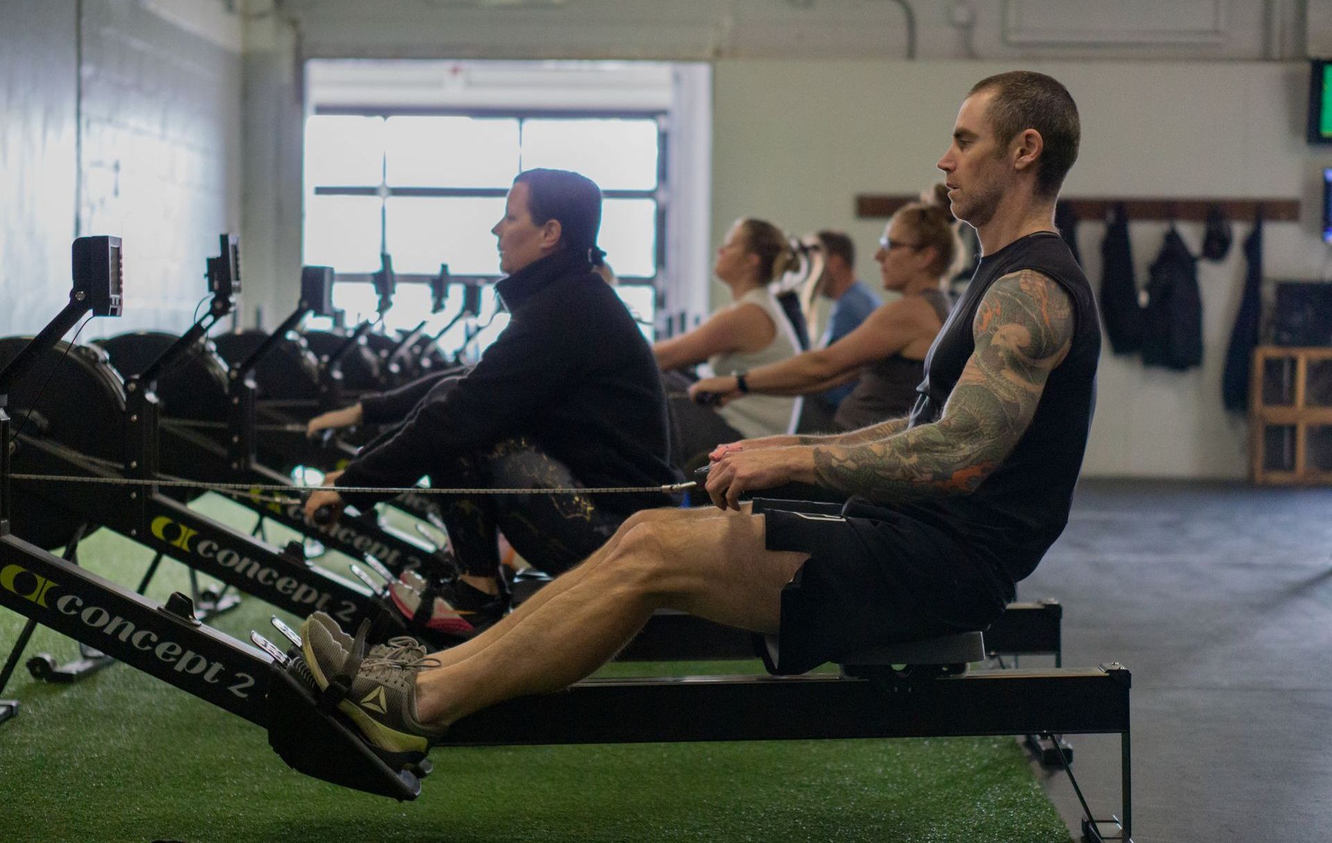 A group of people are rowing rowing machines in a gym.