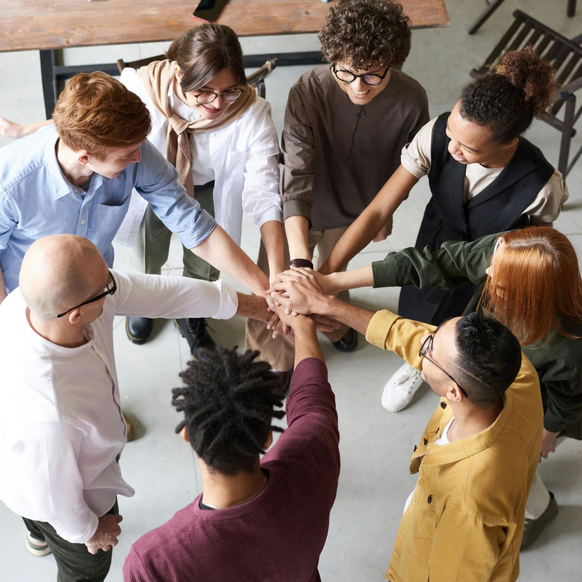 A group of people are putting their hands together in a circle.