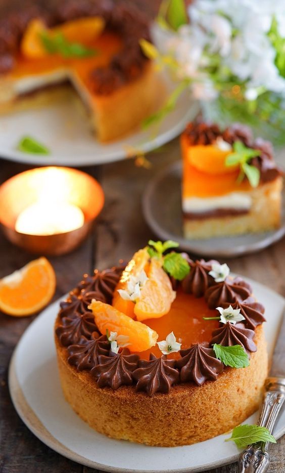 A close up of a cake on a plate with oranges and chocolate frosting.