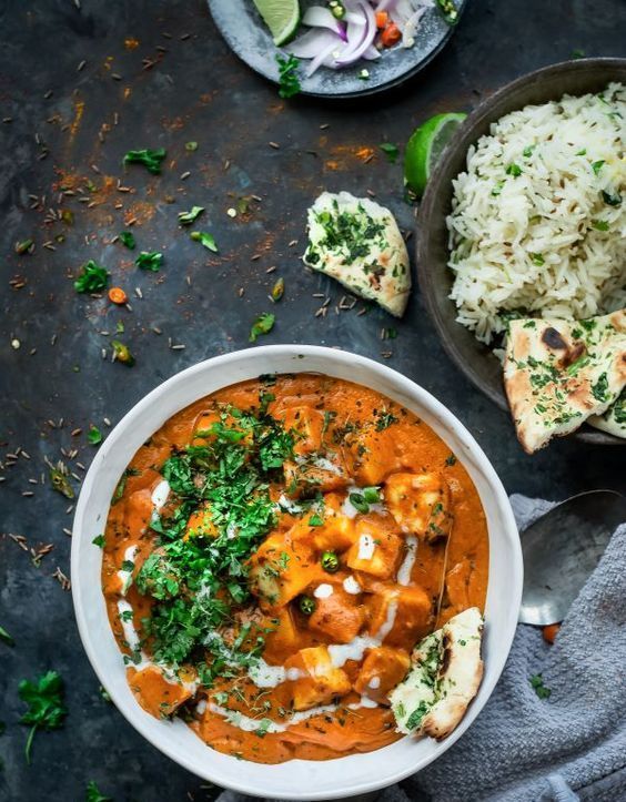 A bowl of food with rice and naan on a table.