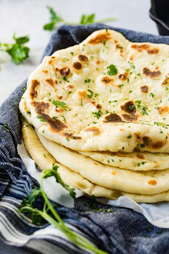 A stack of naan bread in a basket with a fork.