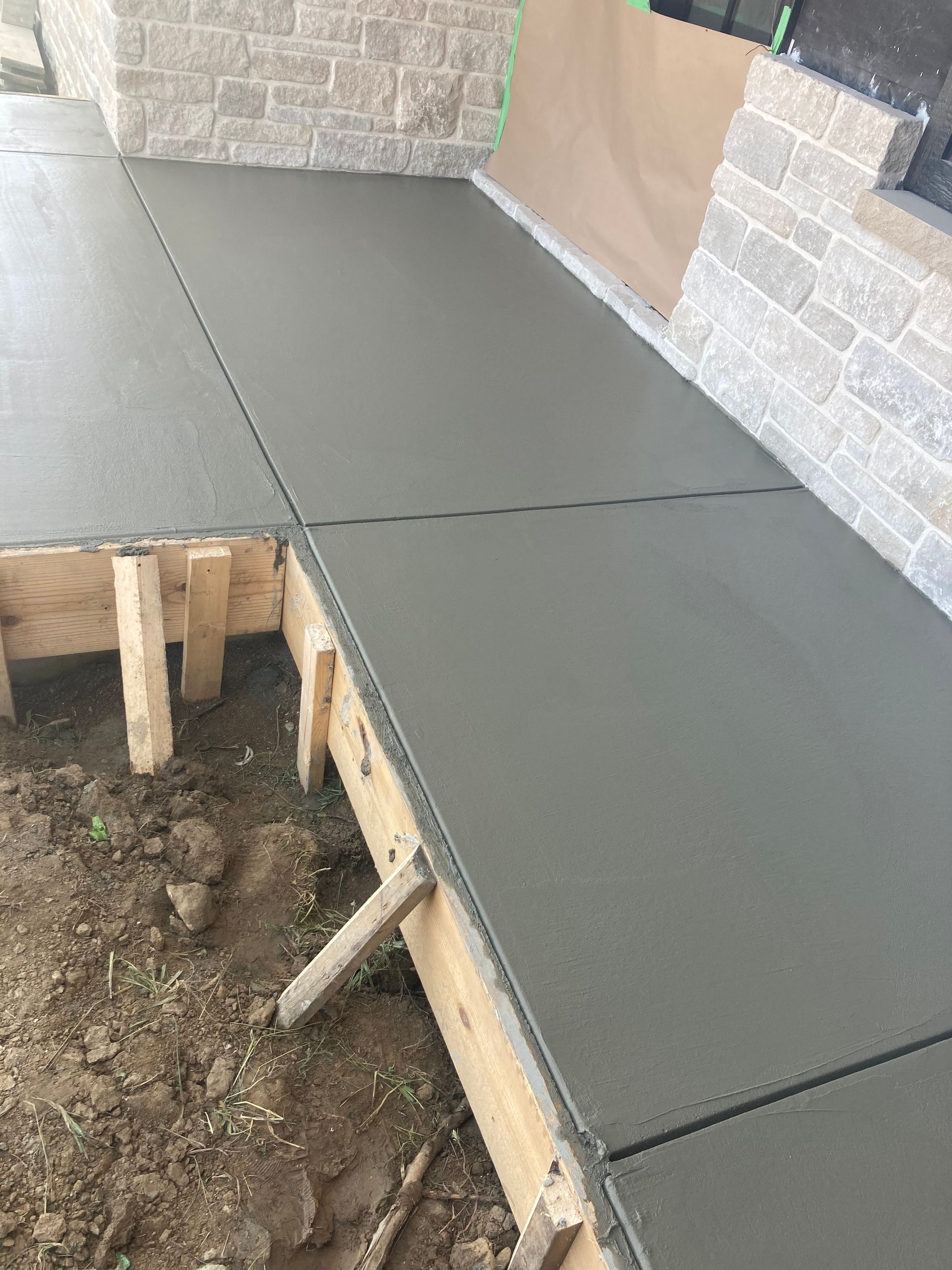 a concrete walkway is being built next to a brick wall .