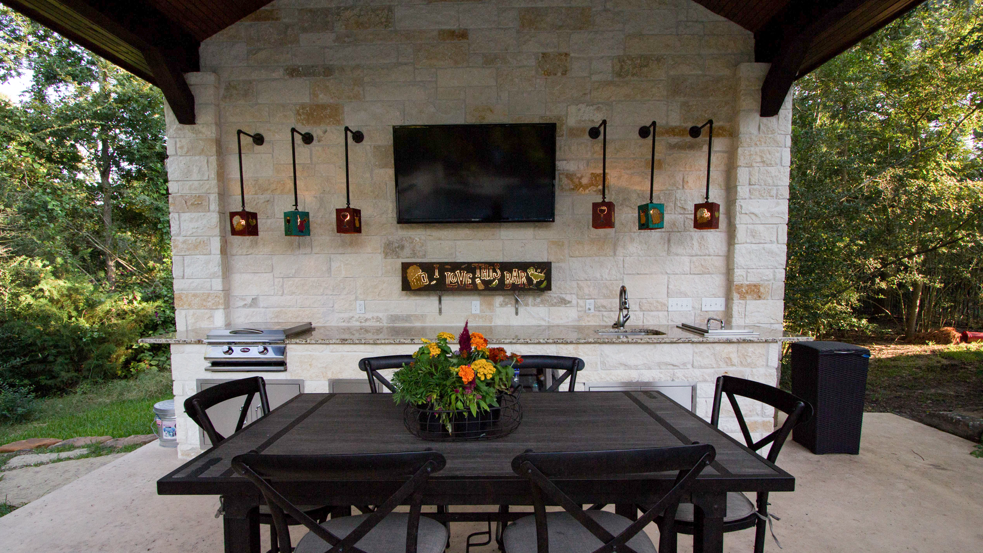 A patio with a table and chairs and a television on the wall.