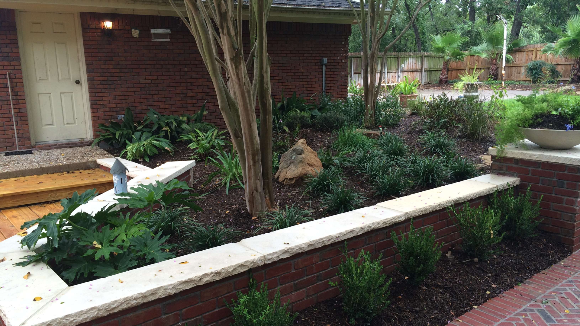 A brick wall with a planter in front of a house.