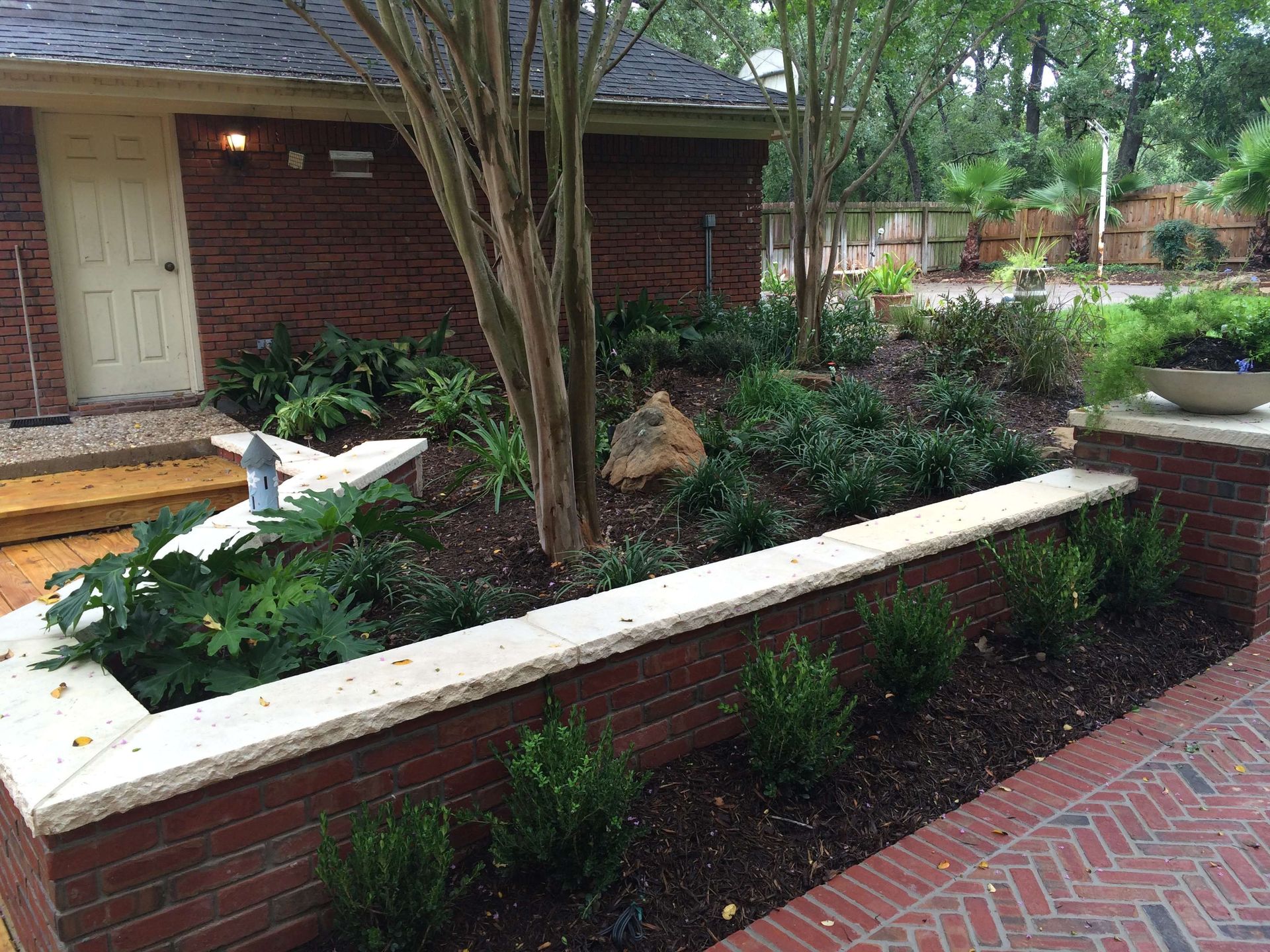 A brick wall with a planter in front of a brick house.